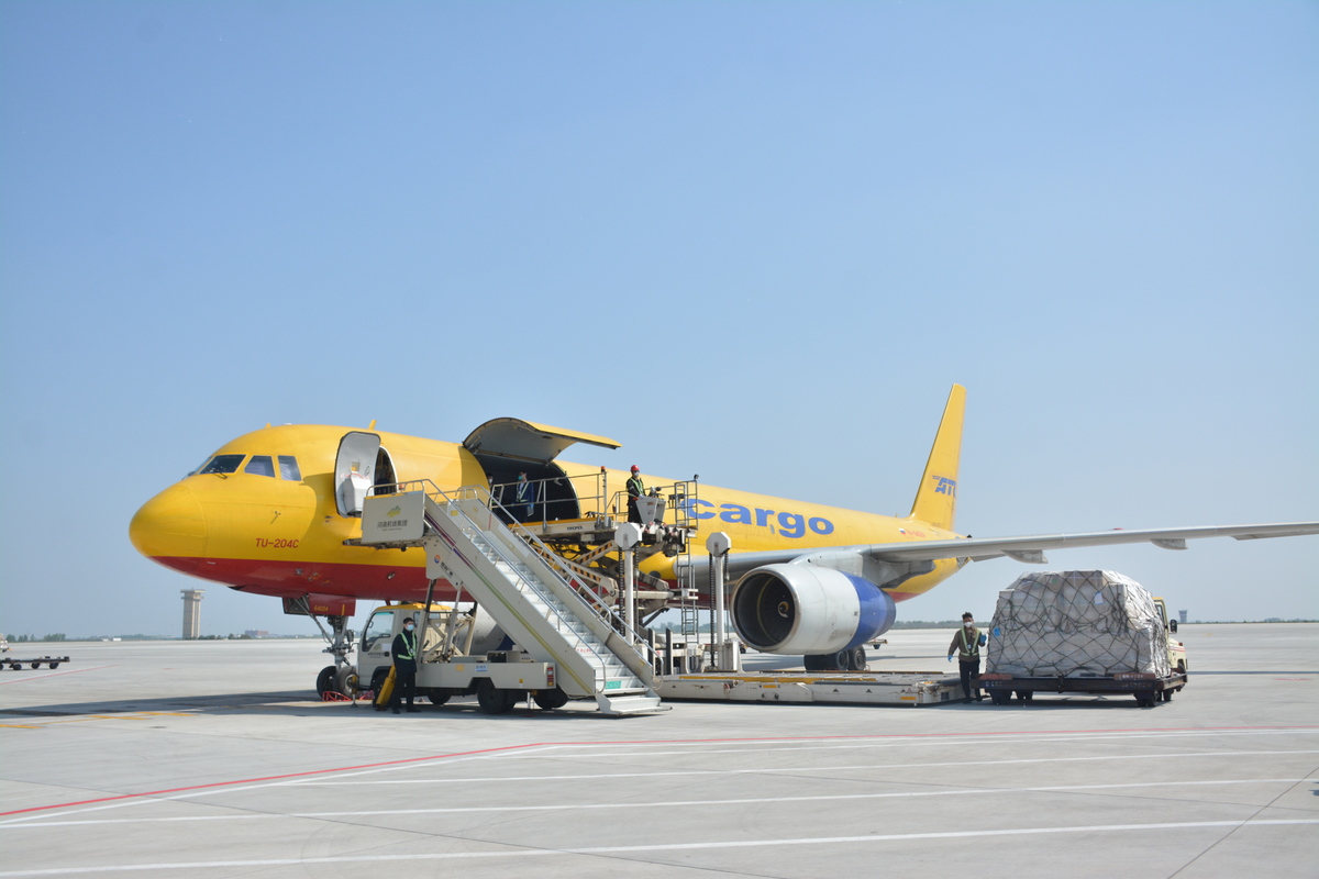 在郑州航空港北货运区,一件件货物正从货运飞机上卸载搬运装车